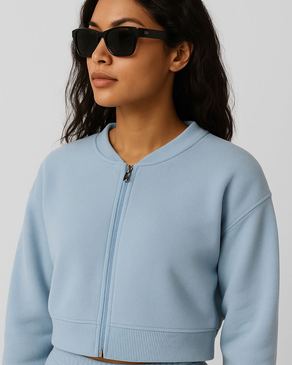 Woman wearing a light blue zip-up sweatshirt against a plain background