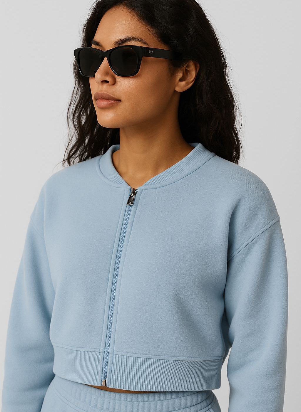 Woman wearing a light blue zip-up sweatshirt against a plain background