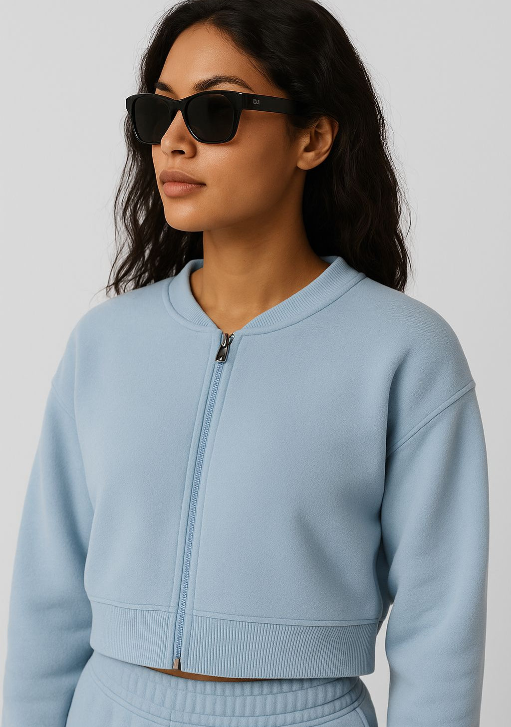 Woman wearing a light blue zip-up sweatshirt against a plain background