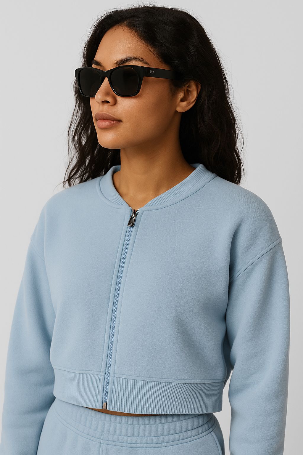 Woman wearing a light blue zip-up sweatshirt against a plain background