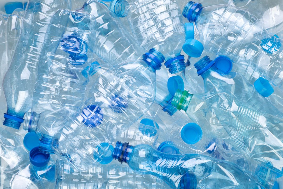 Stack of clear plastic bottles with blue caps on a gray background