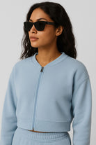 Woman wearing a light blue zip-up sweatshirt against a plain background